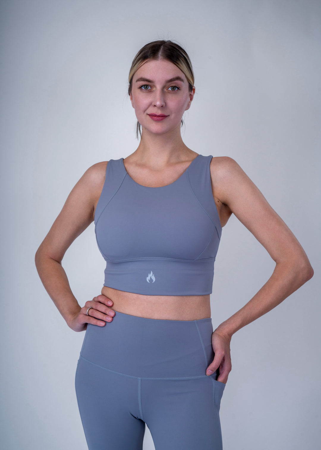 Woman wearing a light blue sports bra and leggings set against a plain background Spofire