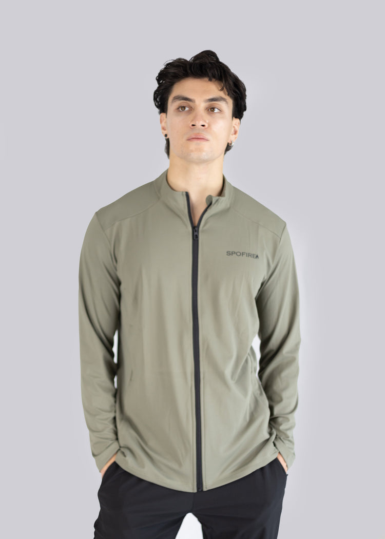 A man wearing an olive  jacket with a brand logo on a gray background