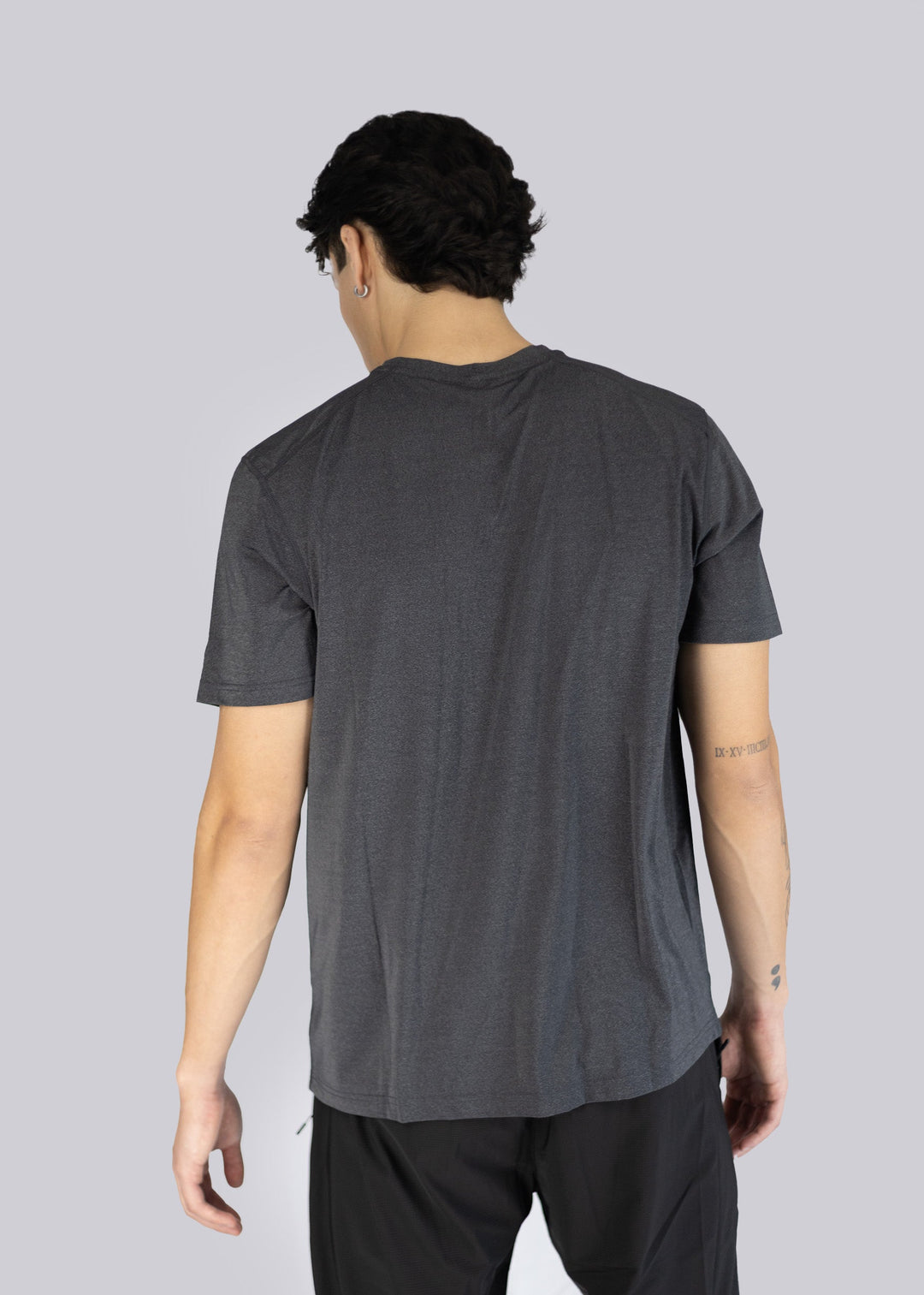 A man wearing a dark gray t-shirt on a light gray background