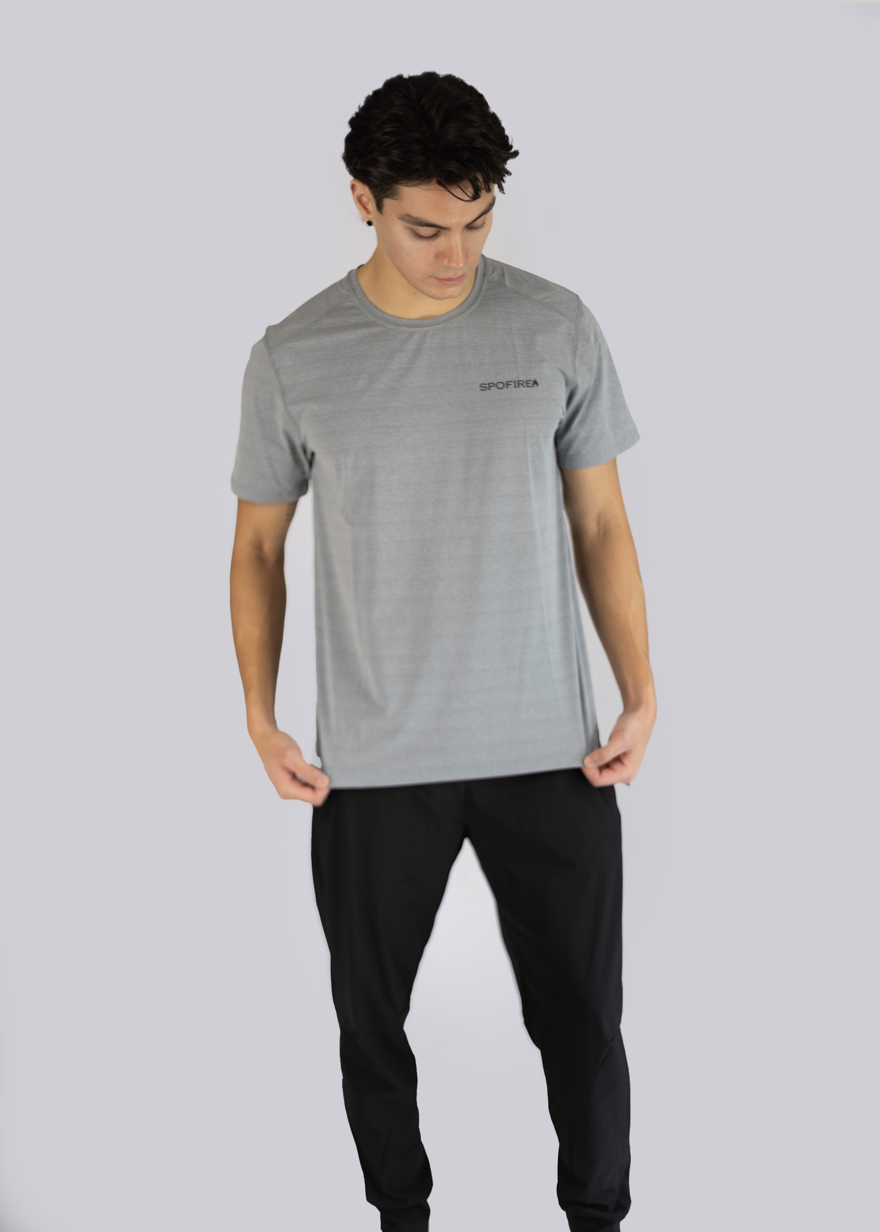 Man wearing a gray t-shirt and black pants on a light gray background