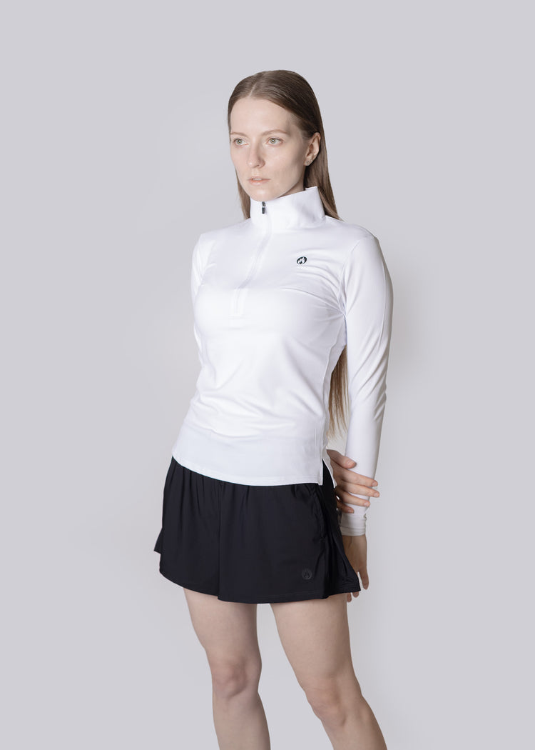 Woman wearing a white long-sleeve top and black Shorts on a light gray background