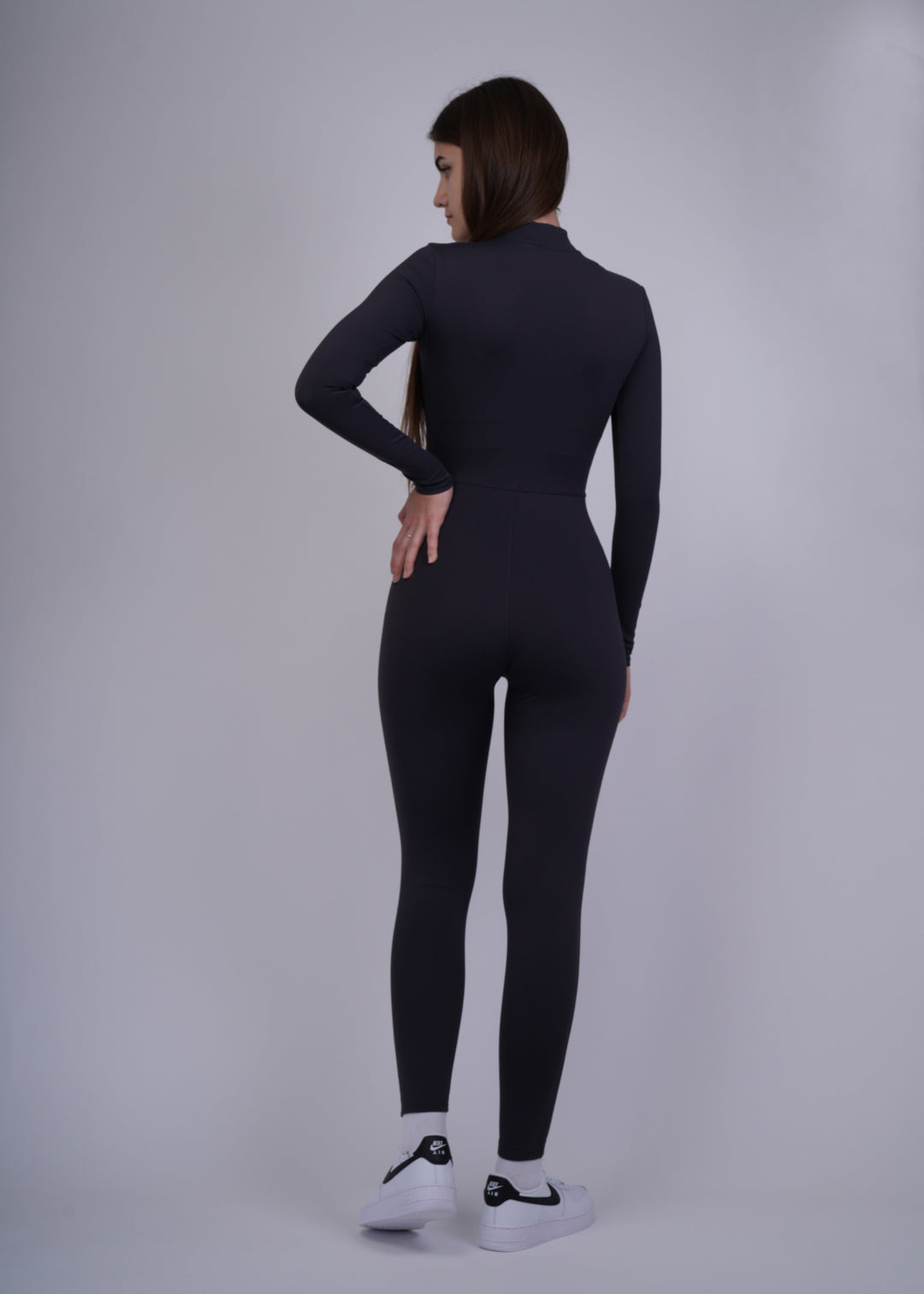 A model wearing a black bodysuit on a plain background