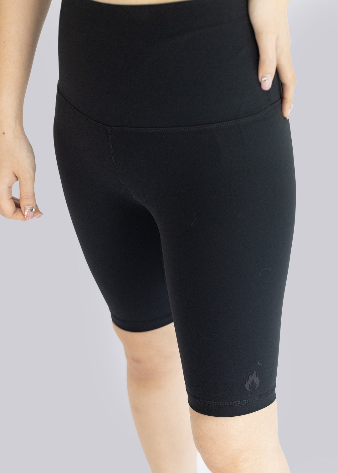Black athletic shorts worn by a Woman on a gray background