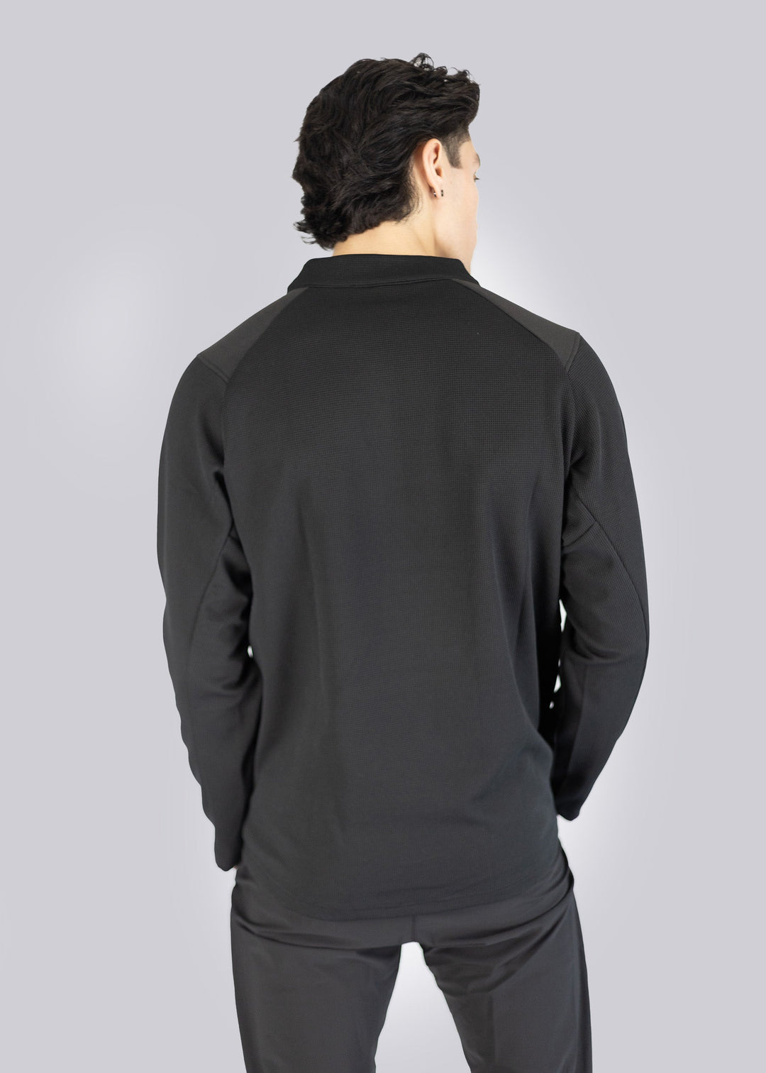 Person wearing a black long-sleeve athletic Sweater on a gray background